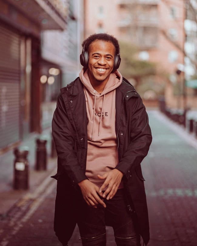 A smiling creator in headphones on a city street